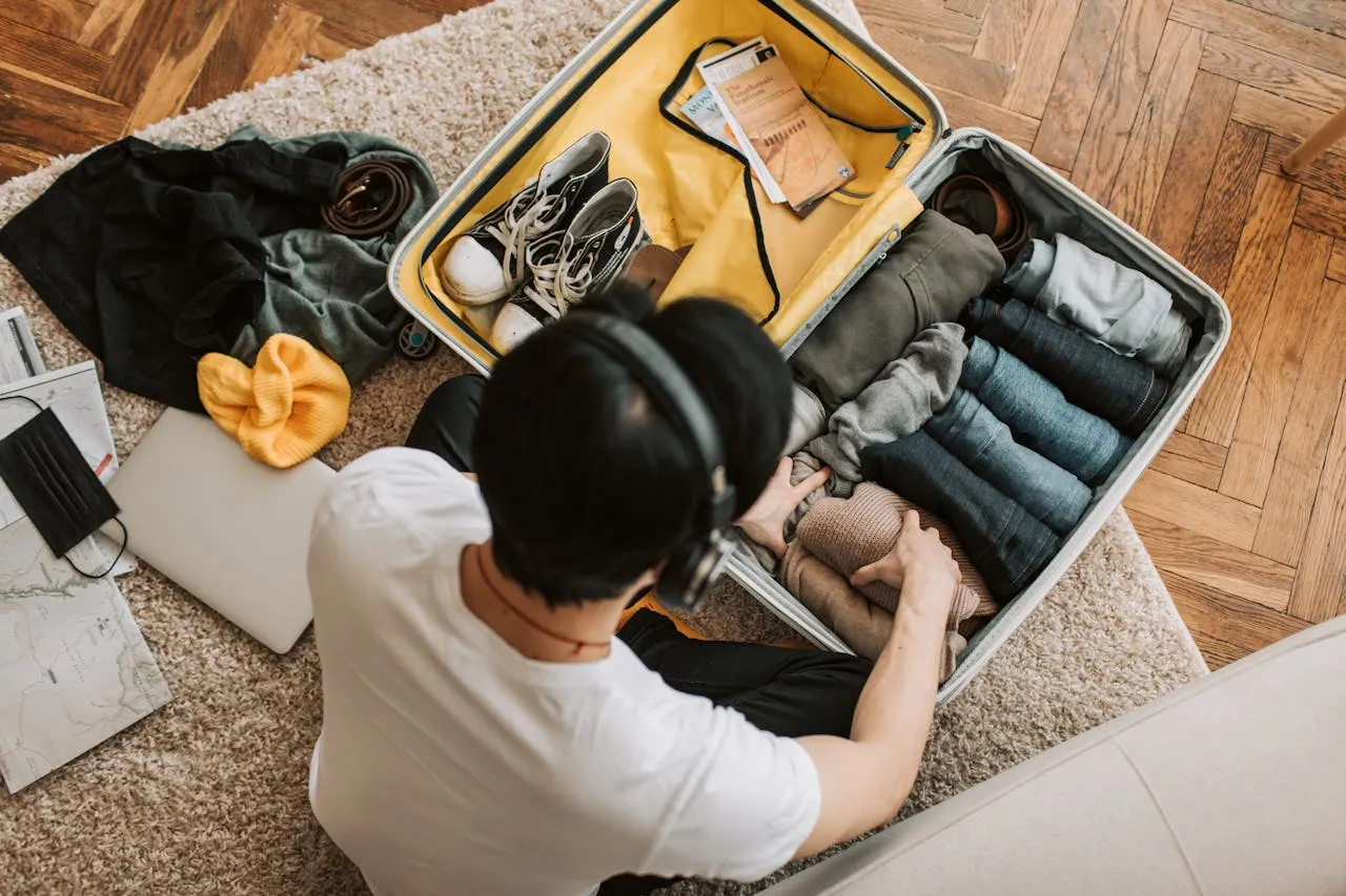 Chico preparando ropa enrollada dentro de una maleta para ahorrar espacio